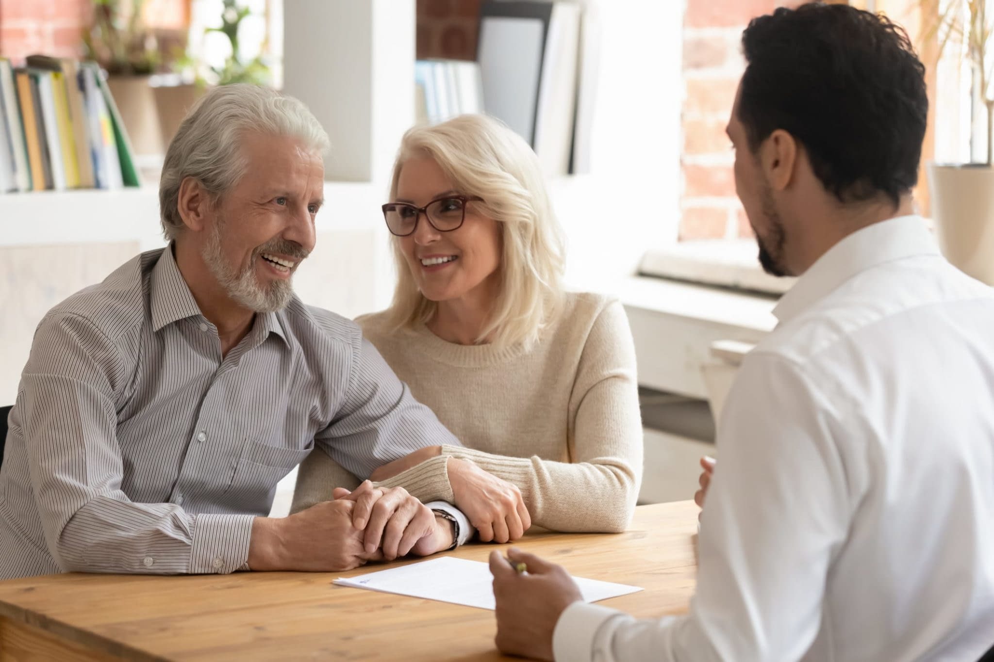 GettyImages-1186603957 Happy Couple Speaking With Life Insurance Agent