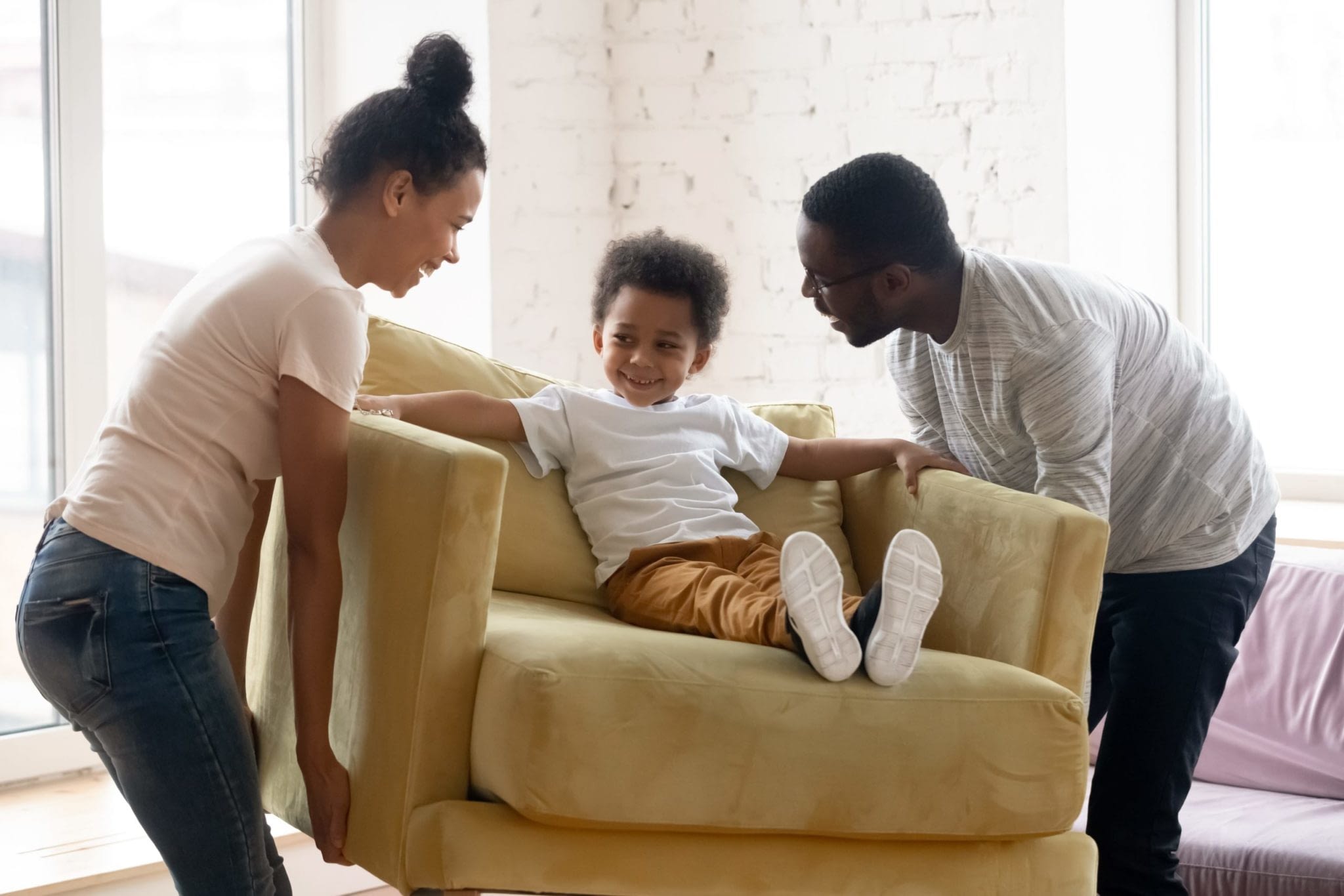 Parents Carrying ArmChair With Son Sitting On It