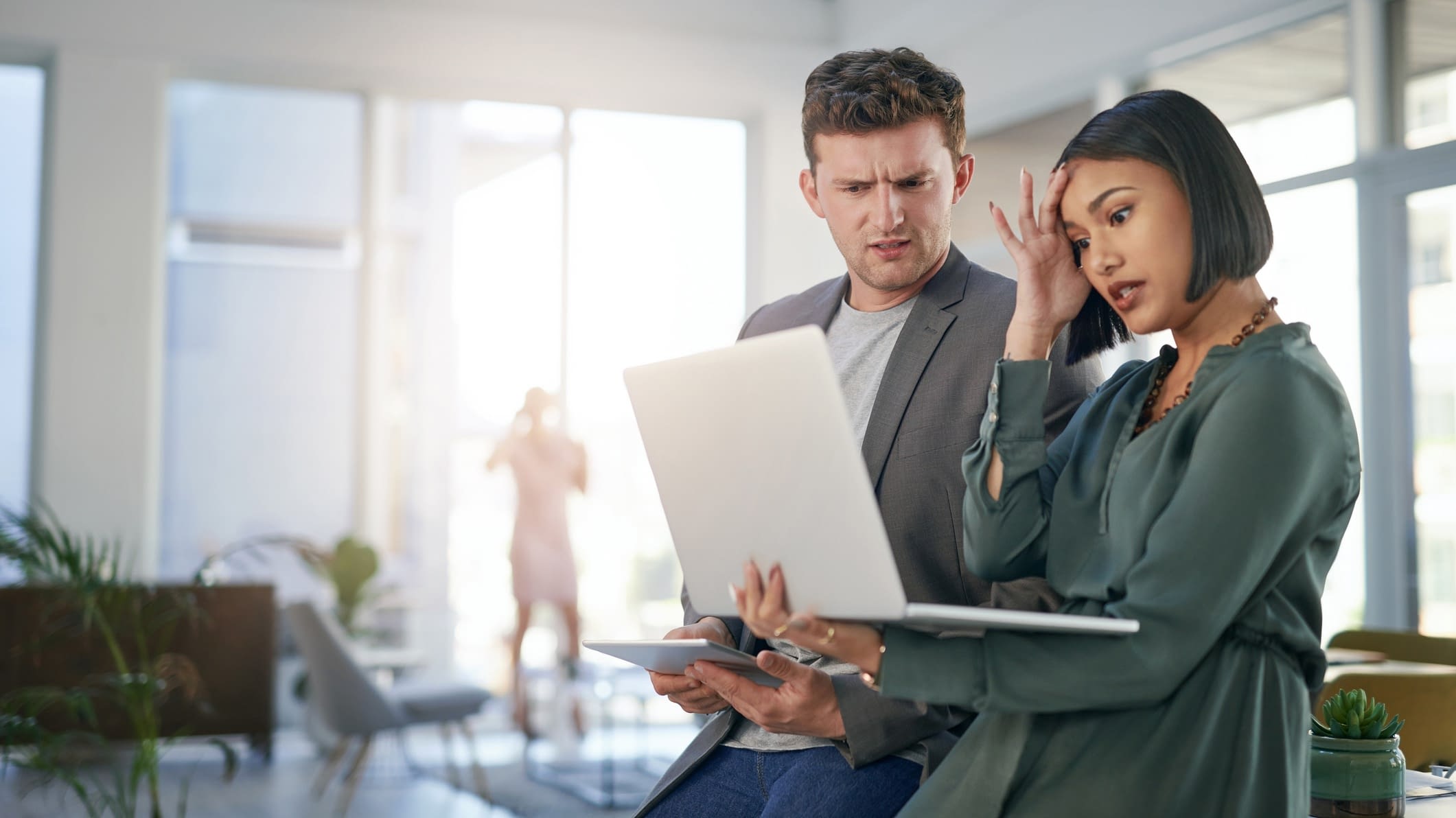 two employees looking at laptop co workers stressed at computer