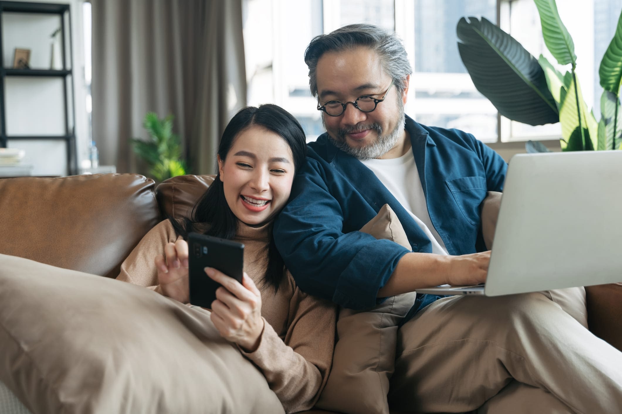 GettyImages-1307229477 Happy Asian Couple Sitting on the Couch