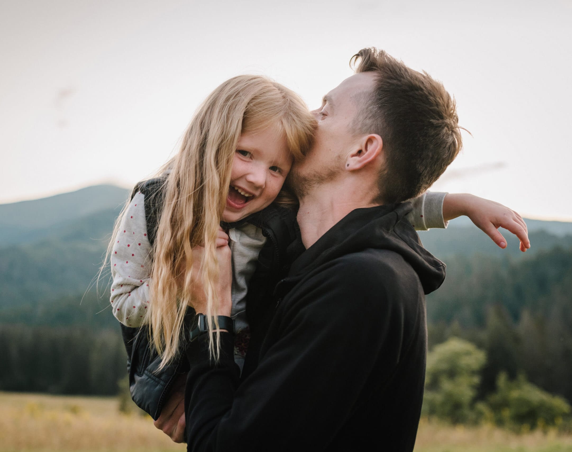 Father throws up his happy daughter into sky with his hands. Walking in nature on an autumn day. Dad and child playing in the mountains. Family spending time together on vacation. World Tourism Day.