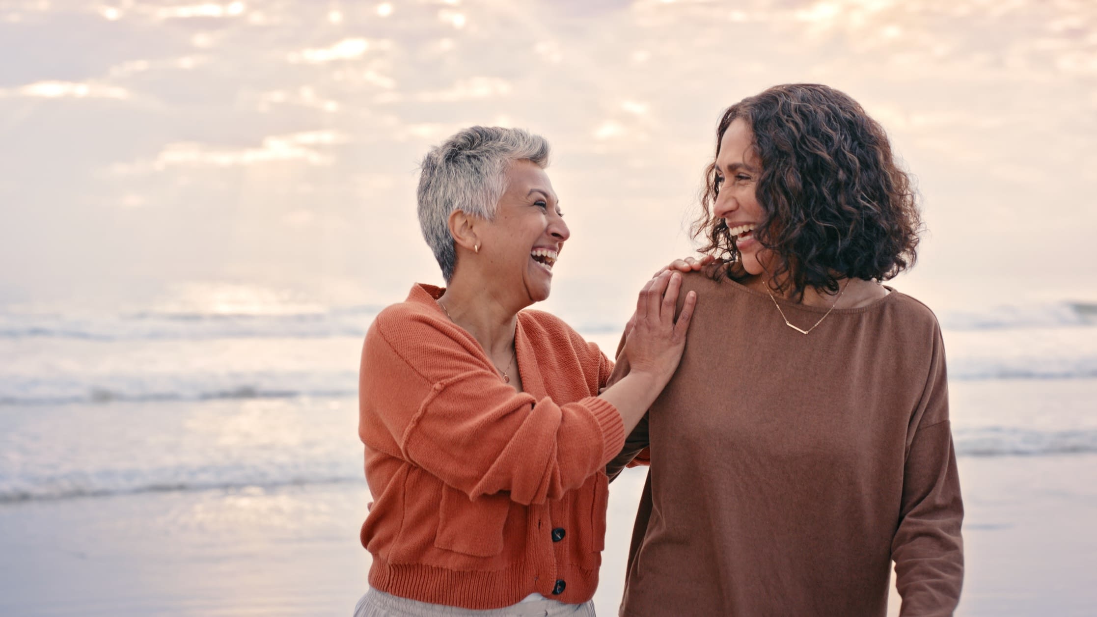 Smiling family members on the beach mature mom and daughter on the beach