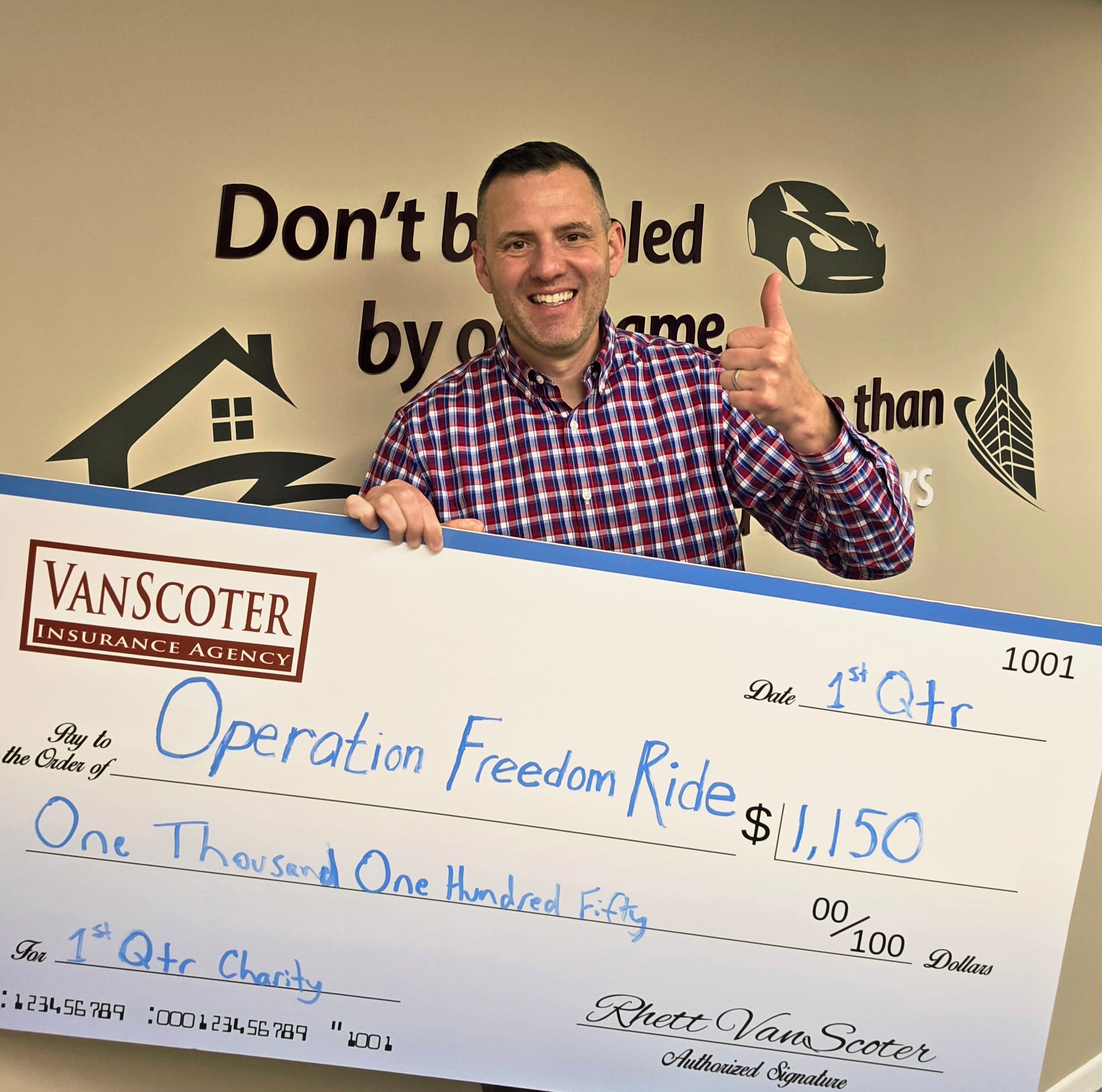 Rhett VanScoter holding oversized $1,150 donation check for Operation Freedom Ride