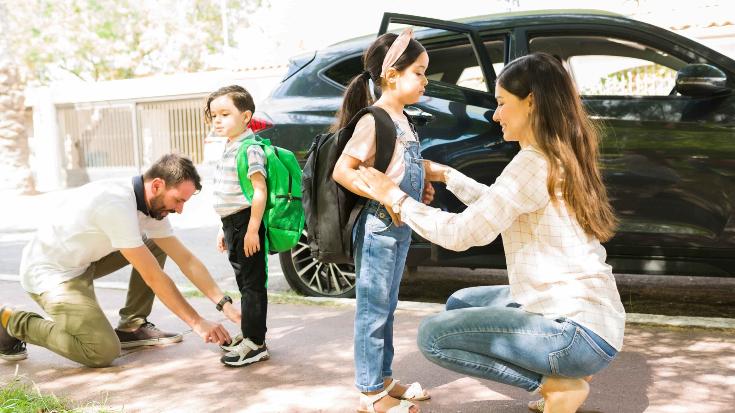 young parents getting son and daughter ready to drive to school