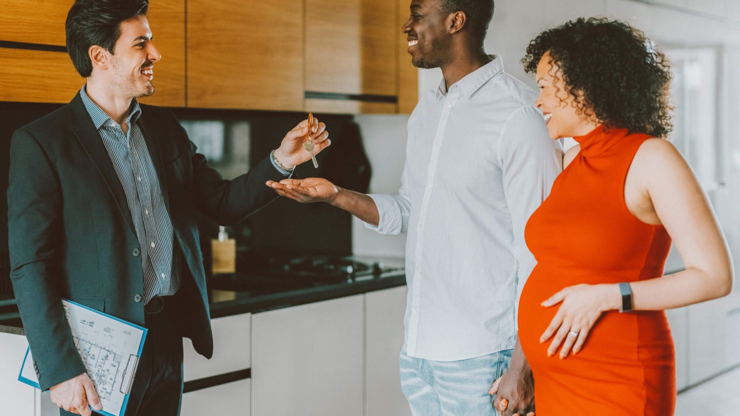 7-7 Blog Image pregnant woman and husband getting key from realtor to new house