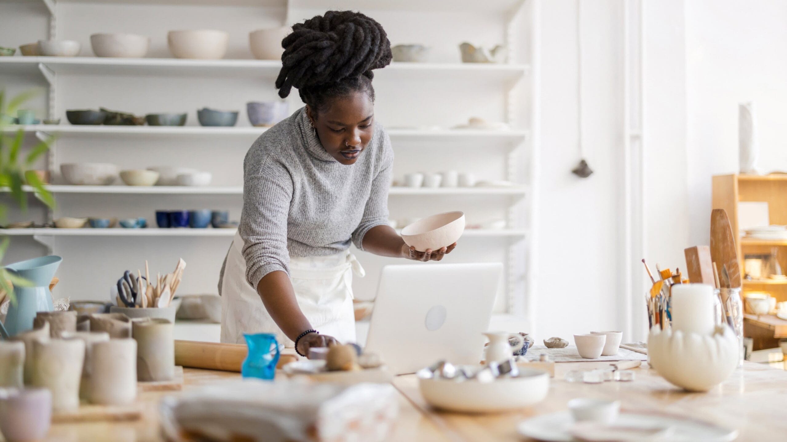 female business owner organizing pottery in her shop