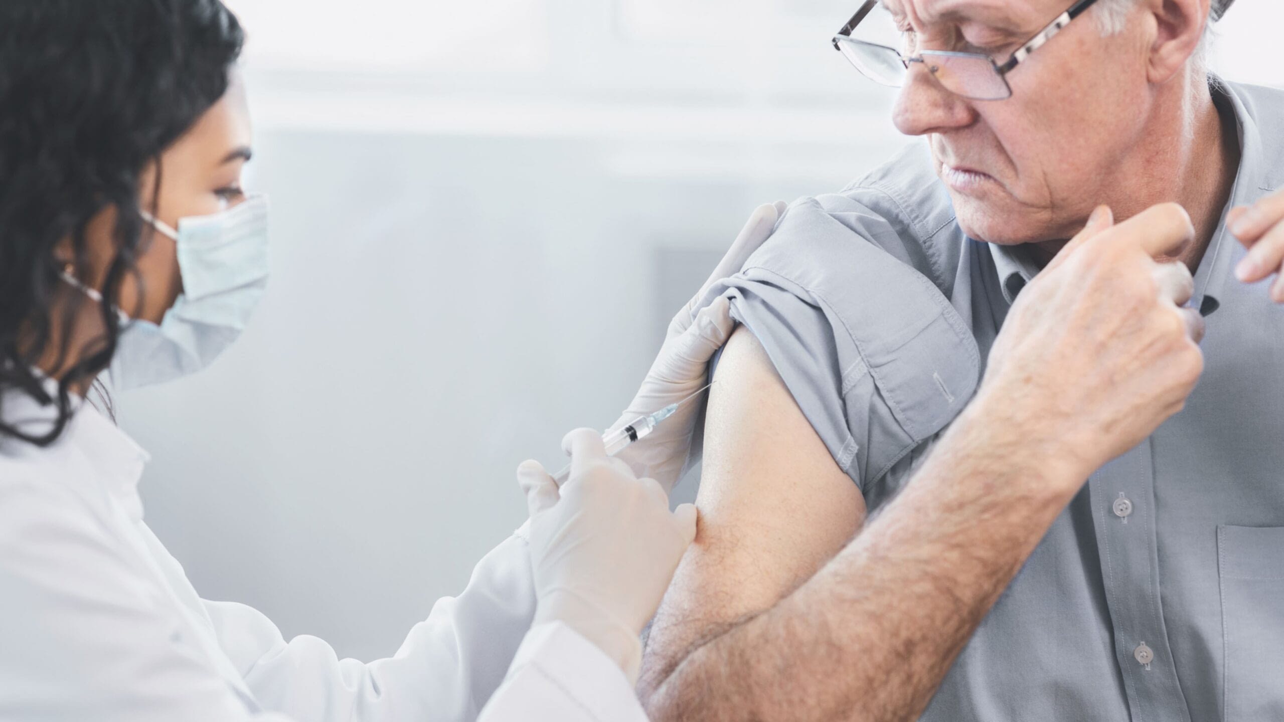 male senior citizen getting immunization shot from doctor