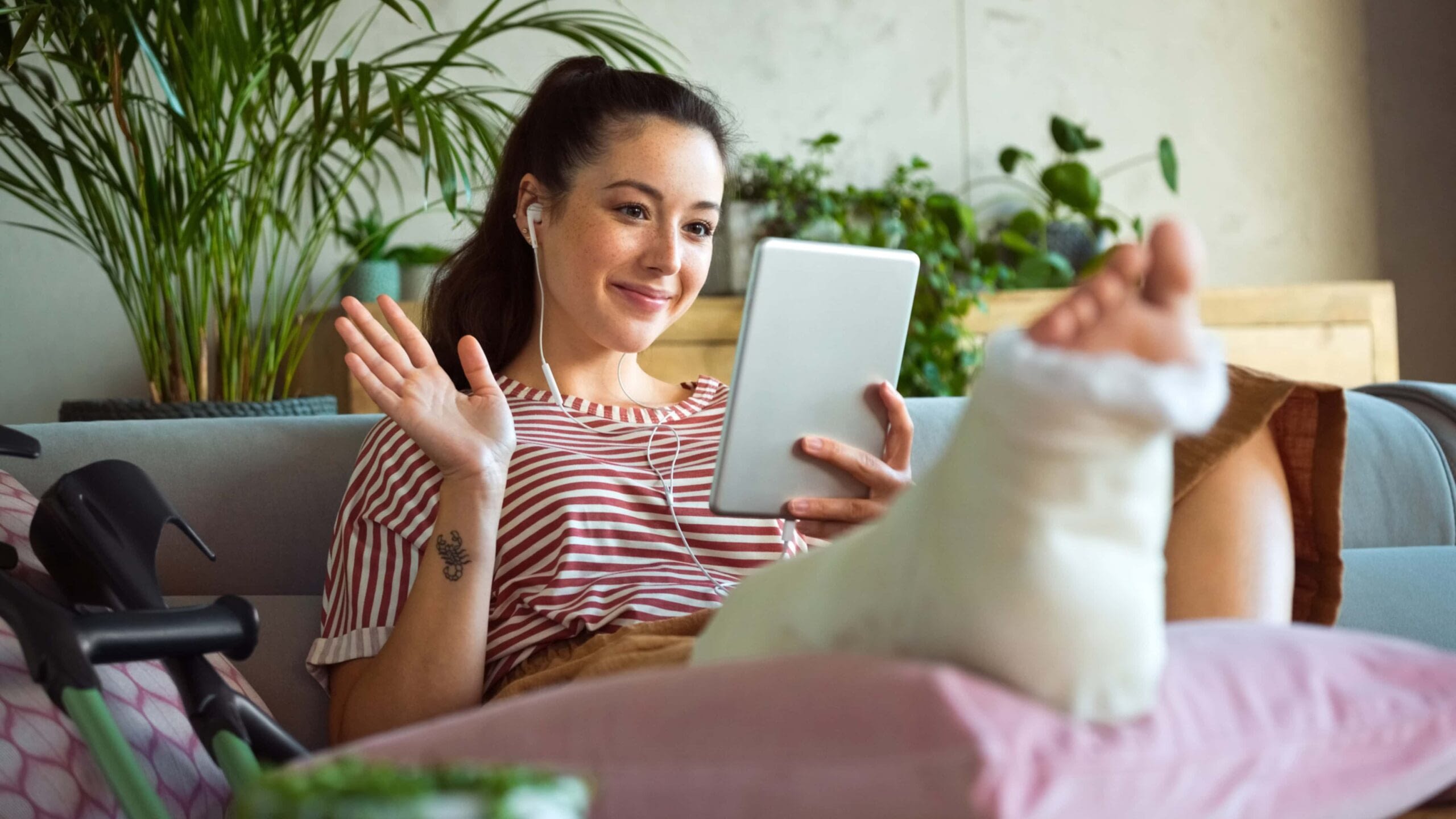 young woman on facetime call with elevated broken foot on pillow