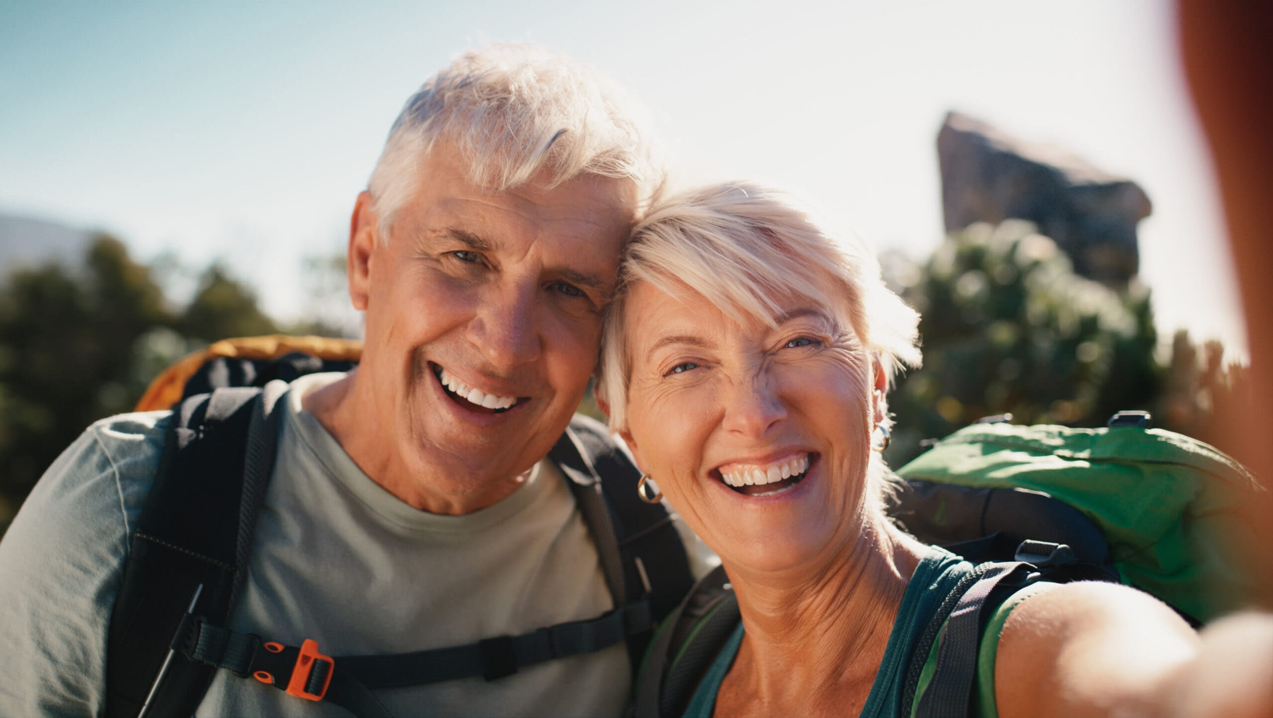 Couple, selfie and portrait in woods, outdoor and backpacking for connection to nature and hiking. Forest, travel and memory of trekking, morning and bonding of mature people, date and photography