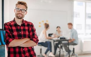 man smiling with arms crossed while people sit in the background