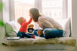 mother and young child relaxing next to a teddy bear with a stay strong shirt
