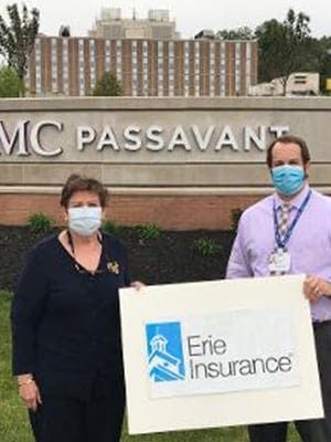 We Don’t Just Sell Policies. We Give Back. Insurance Agents Holding Erie Insurance Sign In Front Of UPMC Passavant Center
