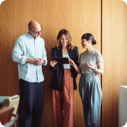 Three colleagues stand together in a modern office