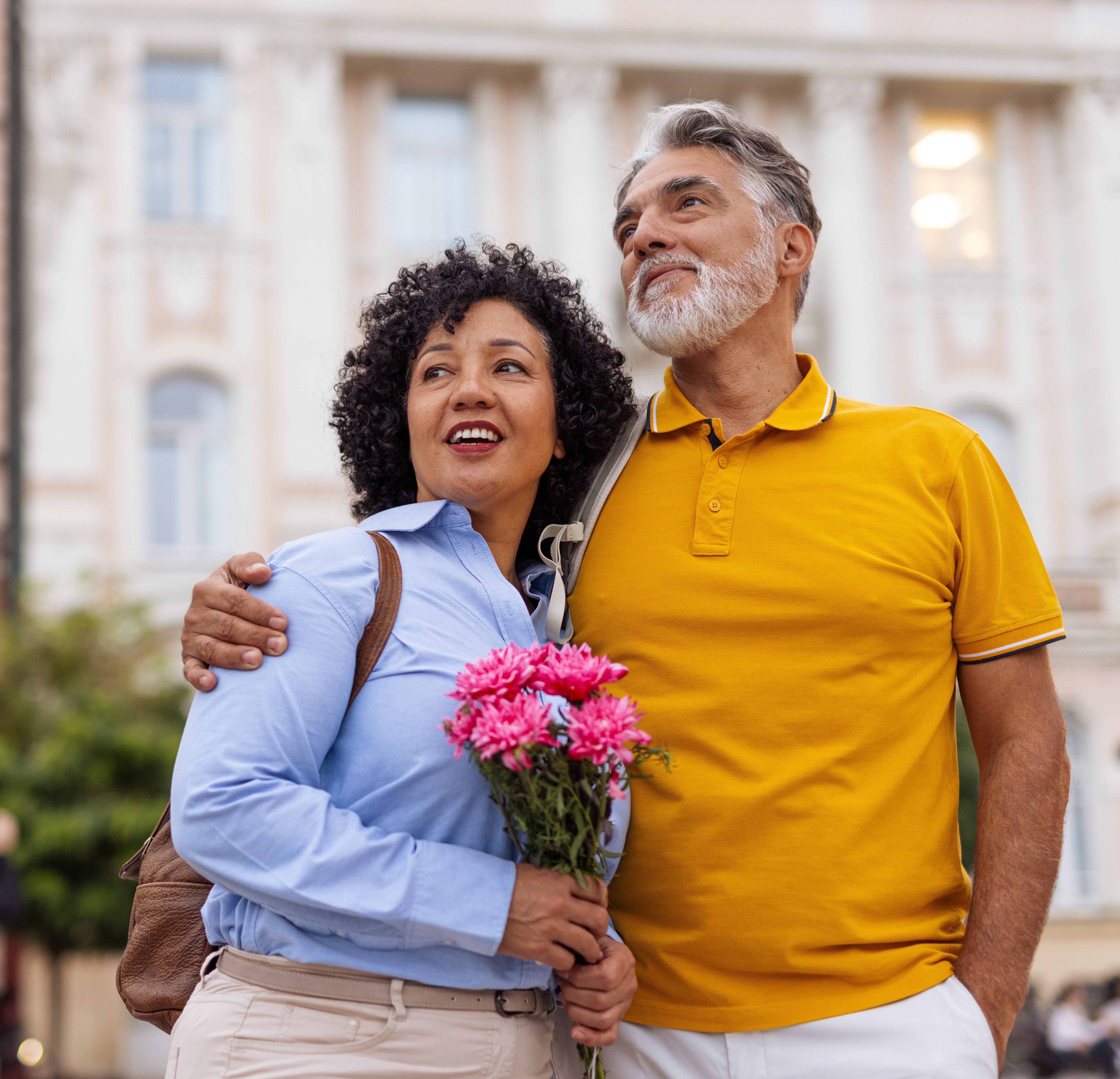 A loving mature couple enjoys a peaceful moment outdoors as the woman lovingly holds a bouquet of fresh flowers in her hands.