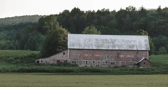 faded_red_barn_in_a_field_575x300