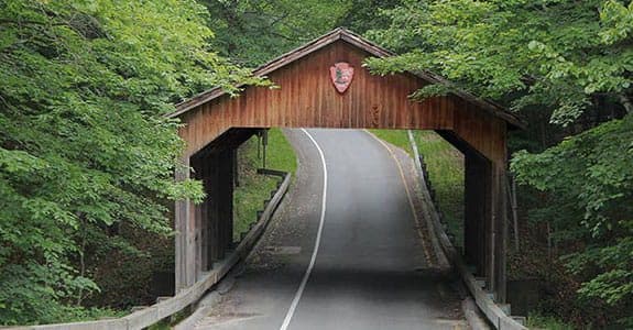 Road going through an old red bridge that has a roof on it