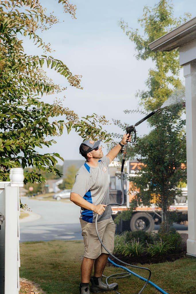 man powerwashing house