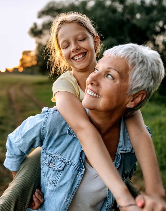 Grandmother carrying her granddaughter on back outdoors