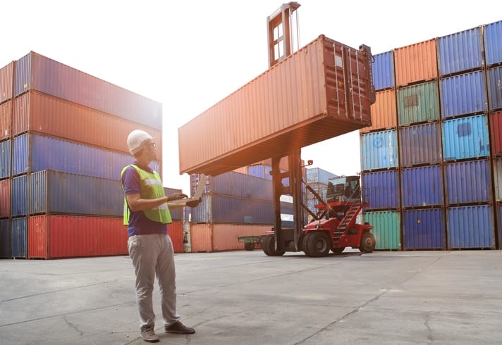 Worker Monitoring Loading Container Being Lifted