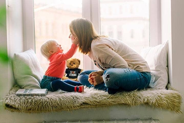 mother and young child relaxing next to a teddy bear with a stay strong shirt