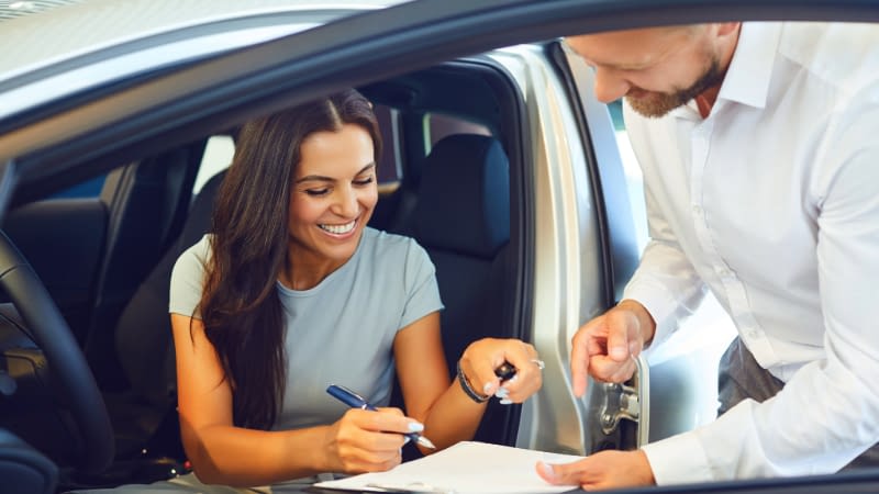 Auto Insurance 6926 Woman signing rental car agreement while sitting in rental car