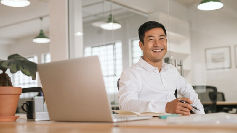 Professional Liability Insurance 81126 Smiling businessman sitting at table with laptop open