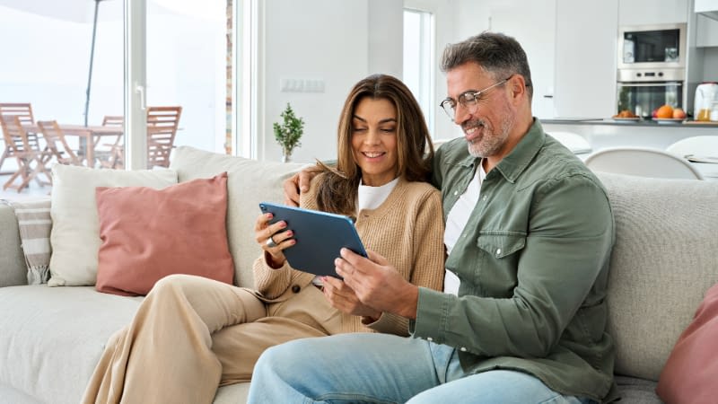 Personal Insurance 102026 Mature couple sitting on couch reviewing their insurance policies on a tablet