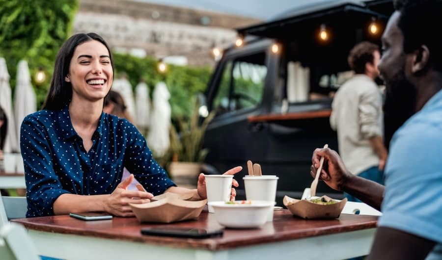 Happy multiracial friends having fun eating in a street food truck