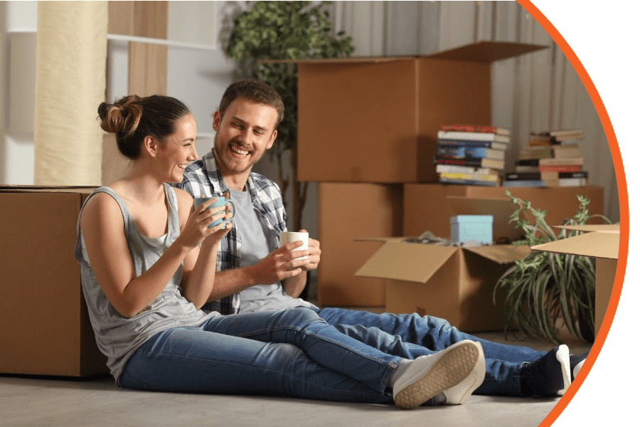 young couple smiling while leaning against moving boxes