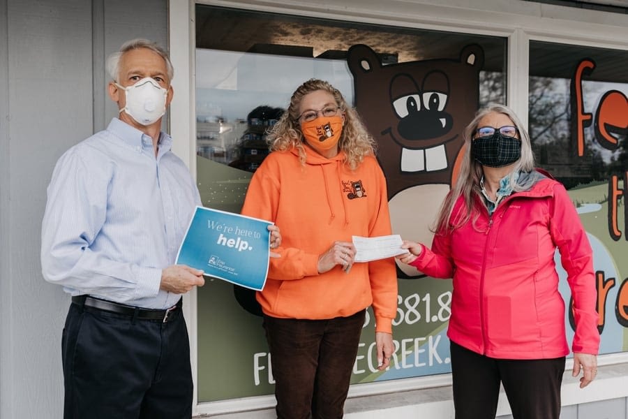 people in masks outside insurance agency with We're Here to Help graphic
