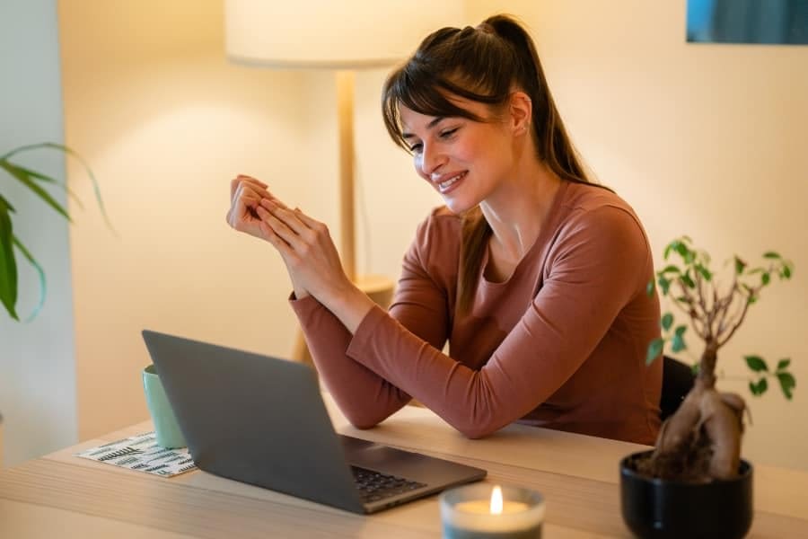Woman smiling while looking at her laptop Woman smiling while looking at her laptop