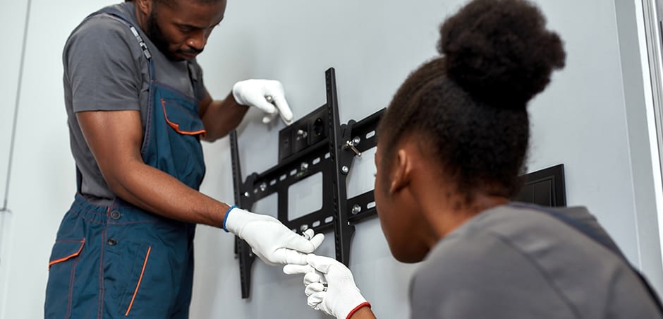 Two people installing tv mount