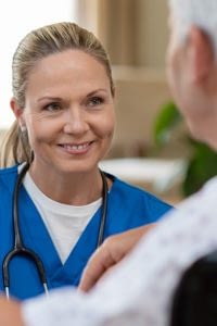 Nurse chatting with a senior woman sitting in a wheelchair.