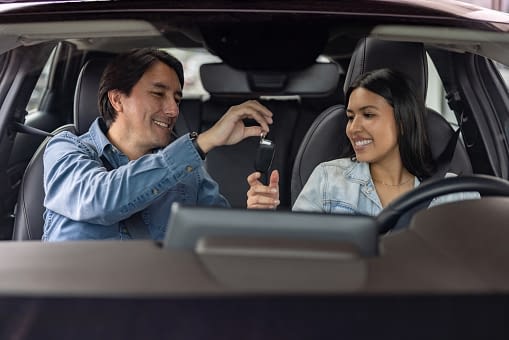 Latin American father teaching his daughter to drive and giving her the car keys â lifestyles concepts