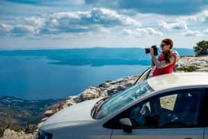 Woman photographer with car on the top of mountain