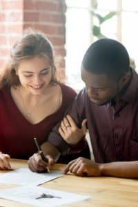 Couple signing paperwork for renters insurance.